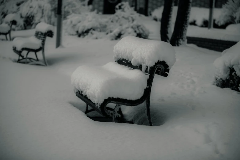 black and white pograph of bench covered with snow