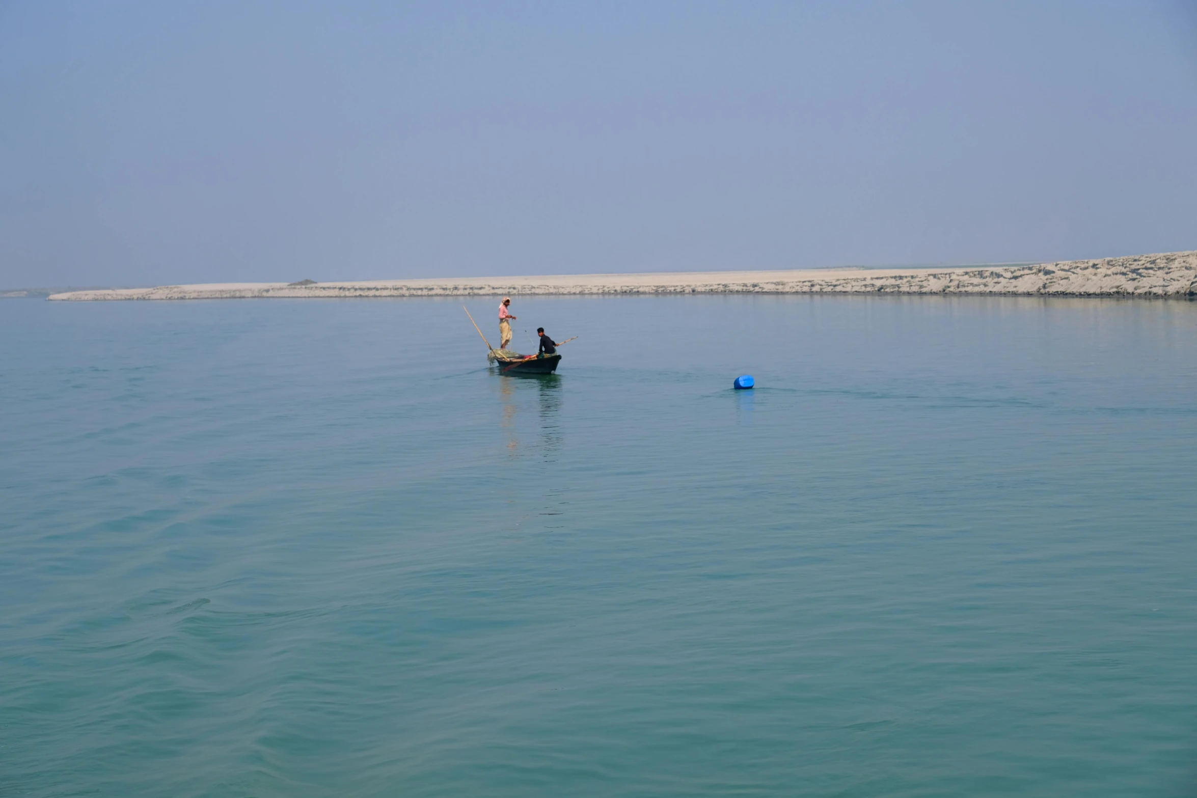 a man fishing on a small boat on clear blue water