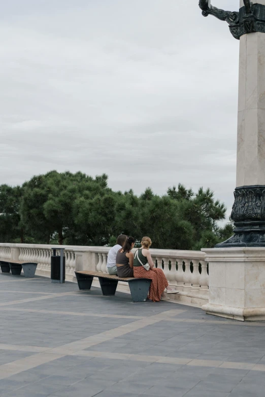 two people sitting on a bench next to a statue