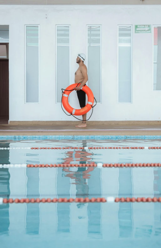 a man is standing in an indoor pool with an inflatable life preserver
