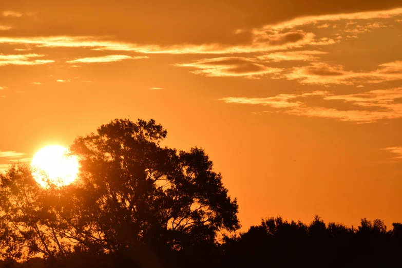 the sun is shining behind the clouds over trees