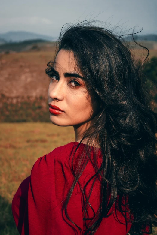 a woman standing in a field looking off to the side