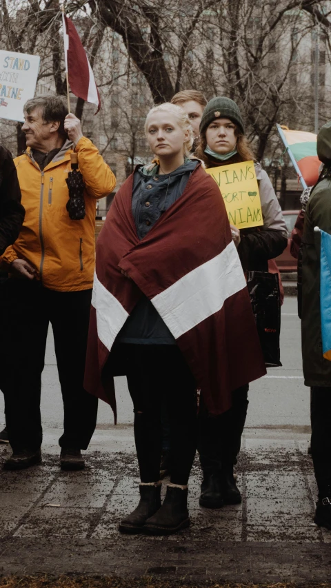 a protester holding a striped blanket and a sign