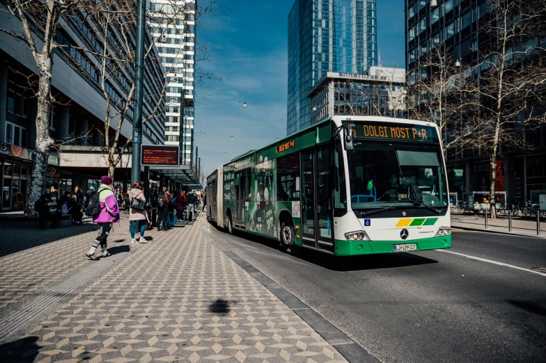 the green and white bus is on the street