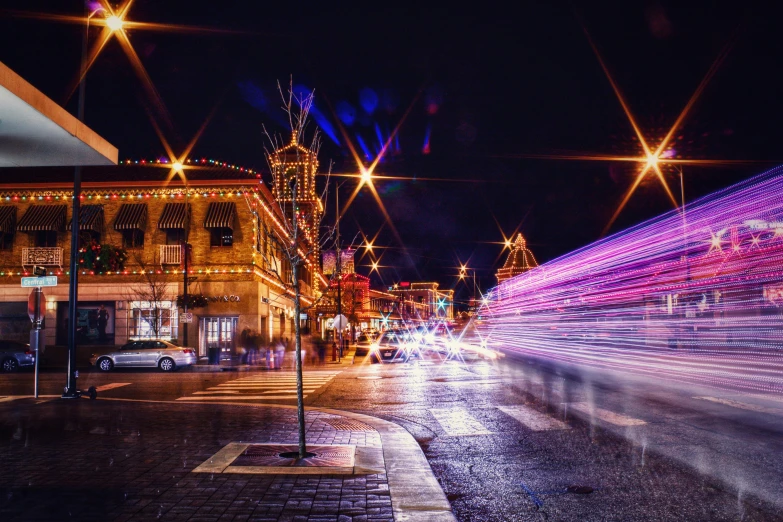 a city at night with lights on the buildings and cars driving down the street