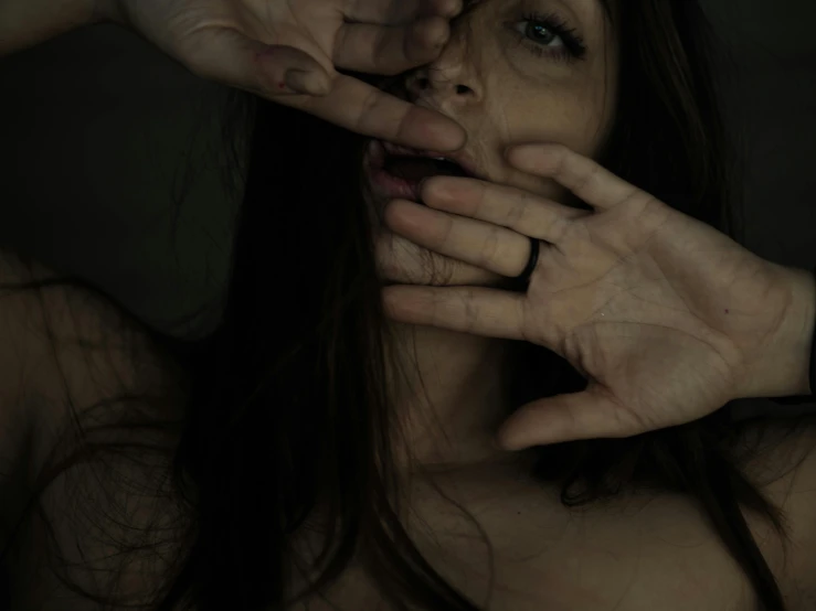 woman's hands over face and fingers on surface of image