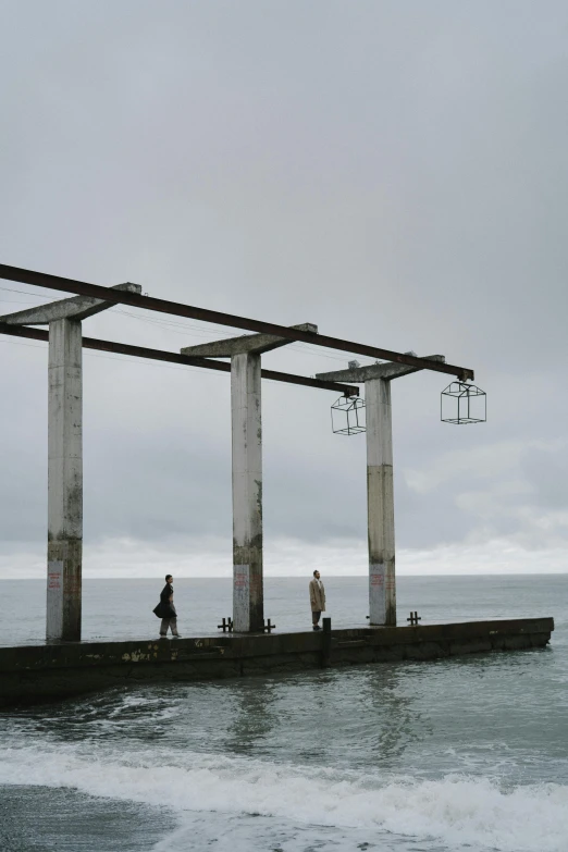 people are walking on a pier next to the ocean