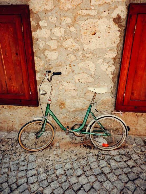 a green bike parked next to a brick building