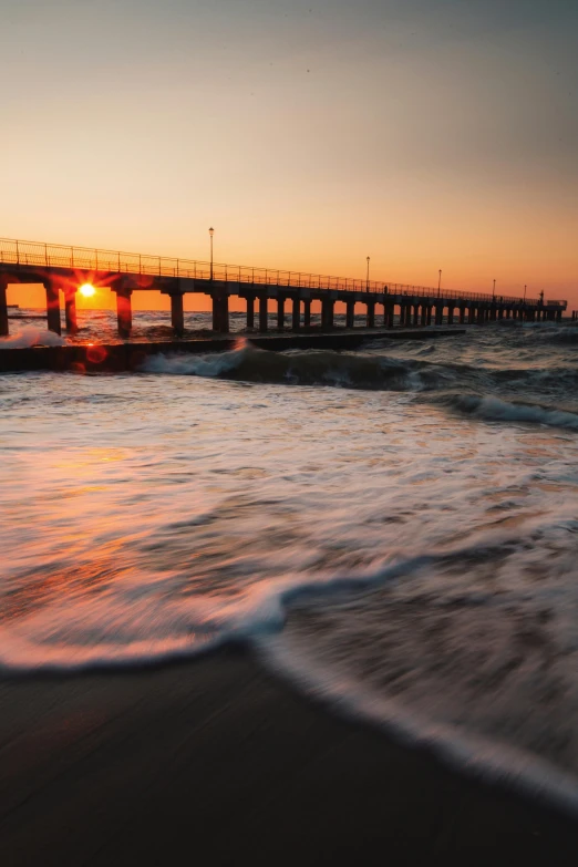 some water waves and a bridge at sunset