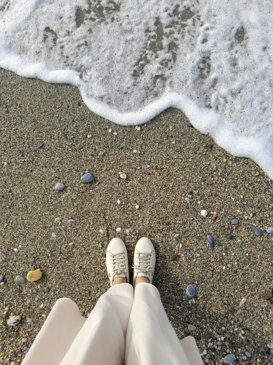 a woman standing on the beach next to a ocean and shore