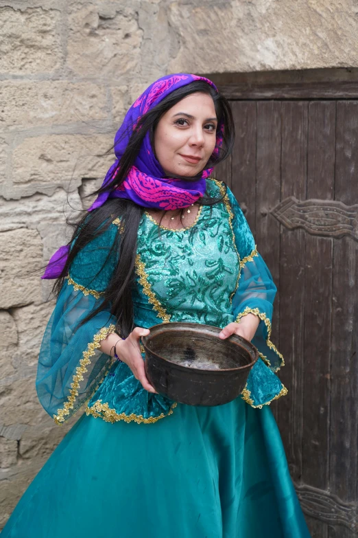 a woman in blue with purple scarf holding a bowl