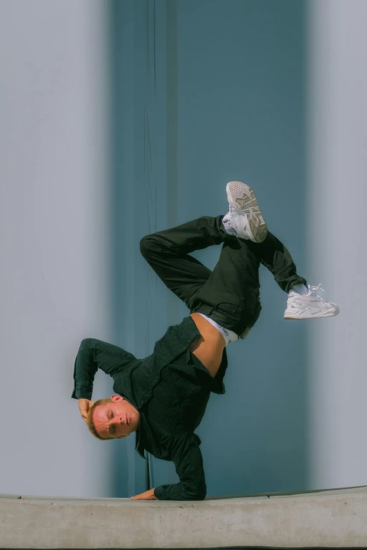 a woman in black with heels on her head does a handstand