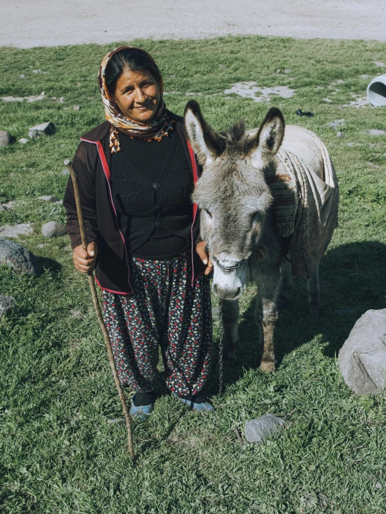 woman standing in grass with donkey in her hands