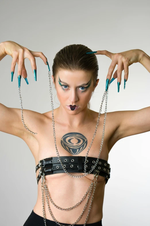 a woman wearing chains around her neck with blue nails and piercing