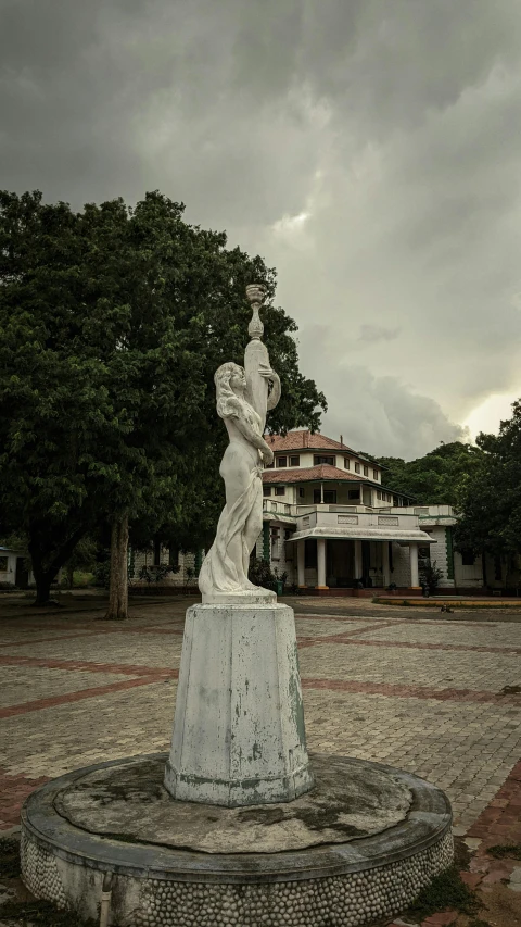 a white statue in a large courtyard with a building in the background