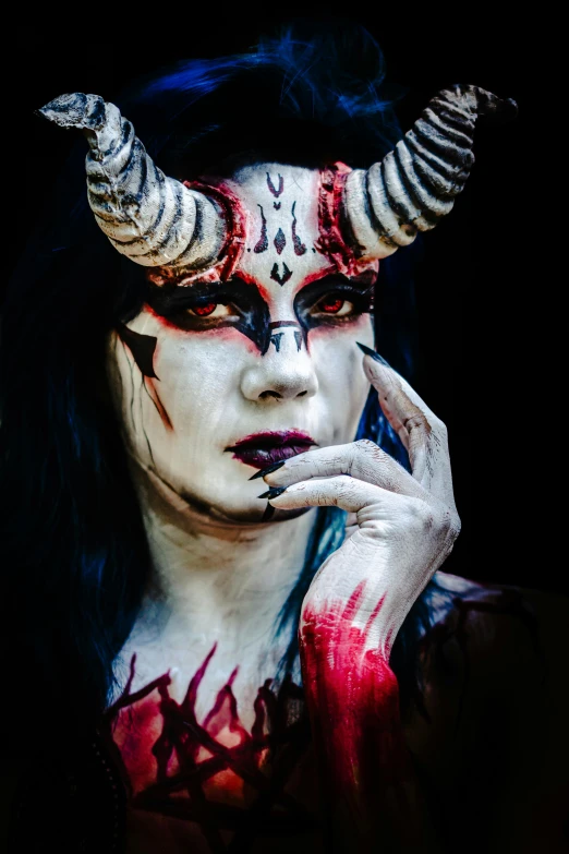 a woman with black and red makeup with horns