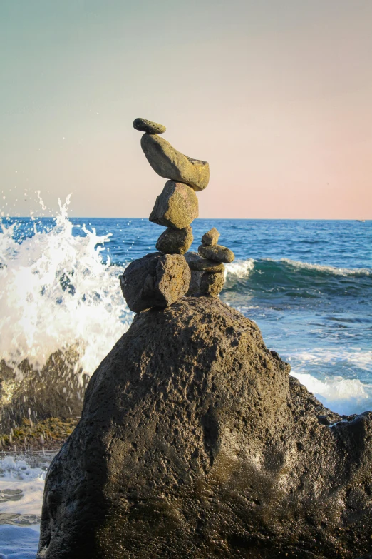 a rock stack stands out against the blue sea waves