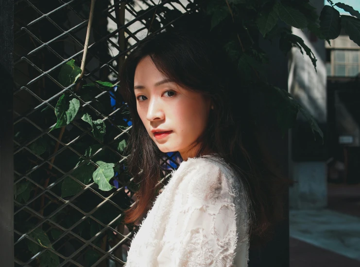 a young lady is standing behind a fence