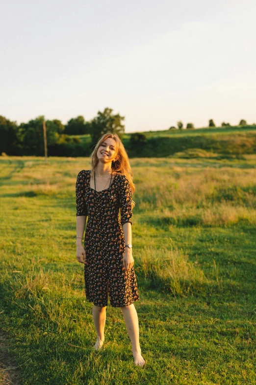 a woman in a dress walking through a field