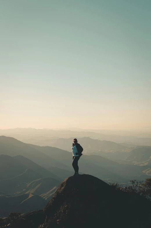 person standing on a hill side top overlooking the valley below