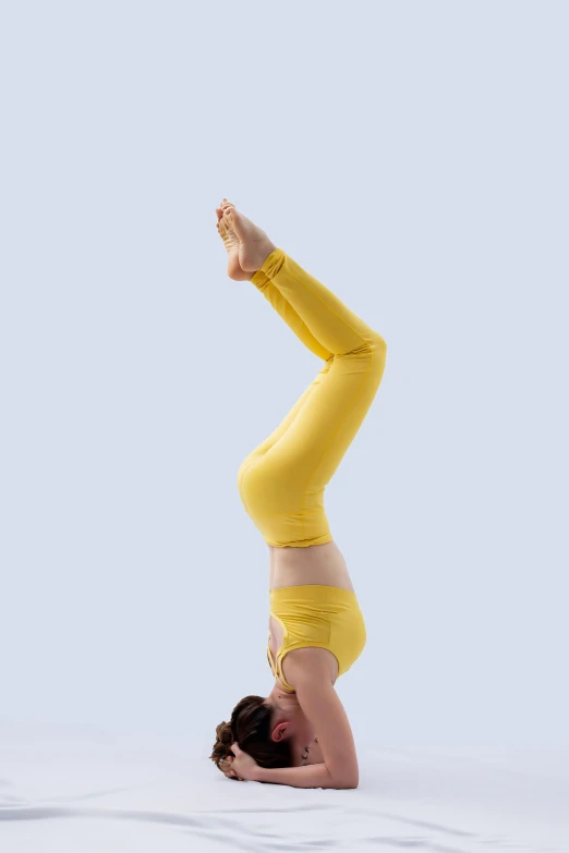 a woman wearing yellow doing a handstand pose