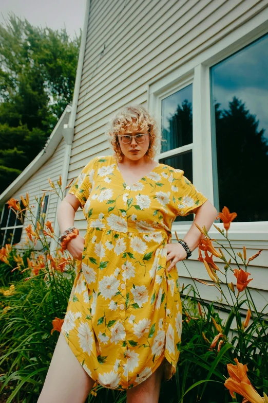 the woman is wearing a dress and sunglasses standing near flowers