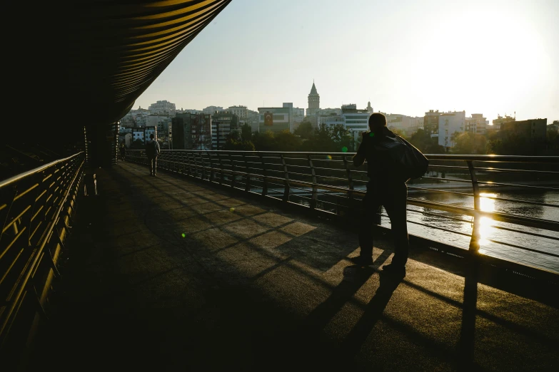 a person is walking along the bridge looking toward the city
