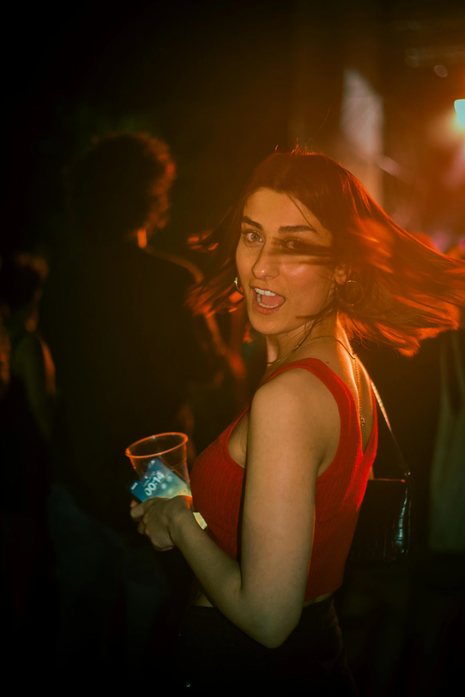 a girl holds a drink while dancing in the dark