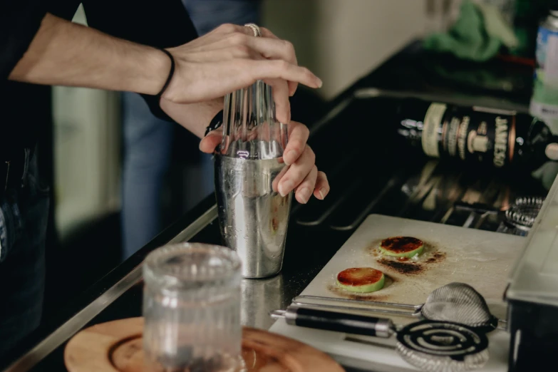 a person blends an ingredients into a cocktail shaker