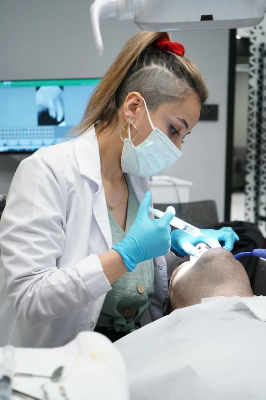 a woman dentist with a surgical mask on working on someones tooth