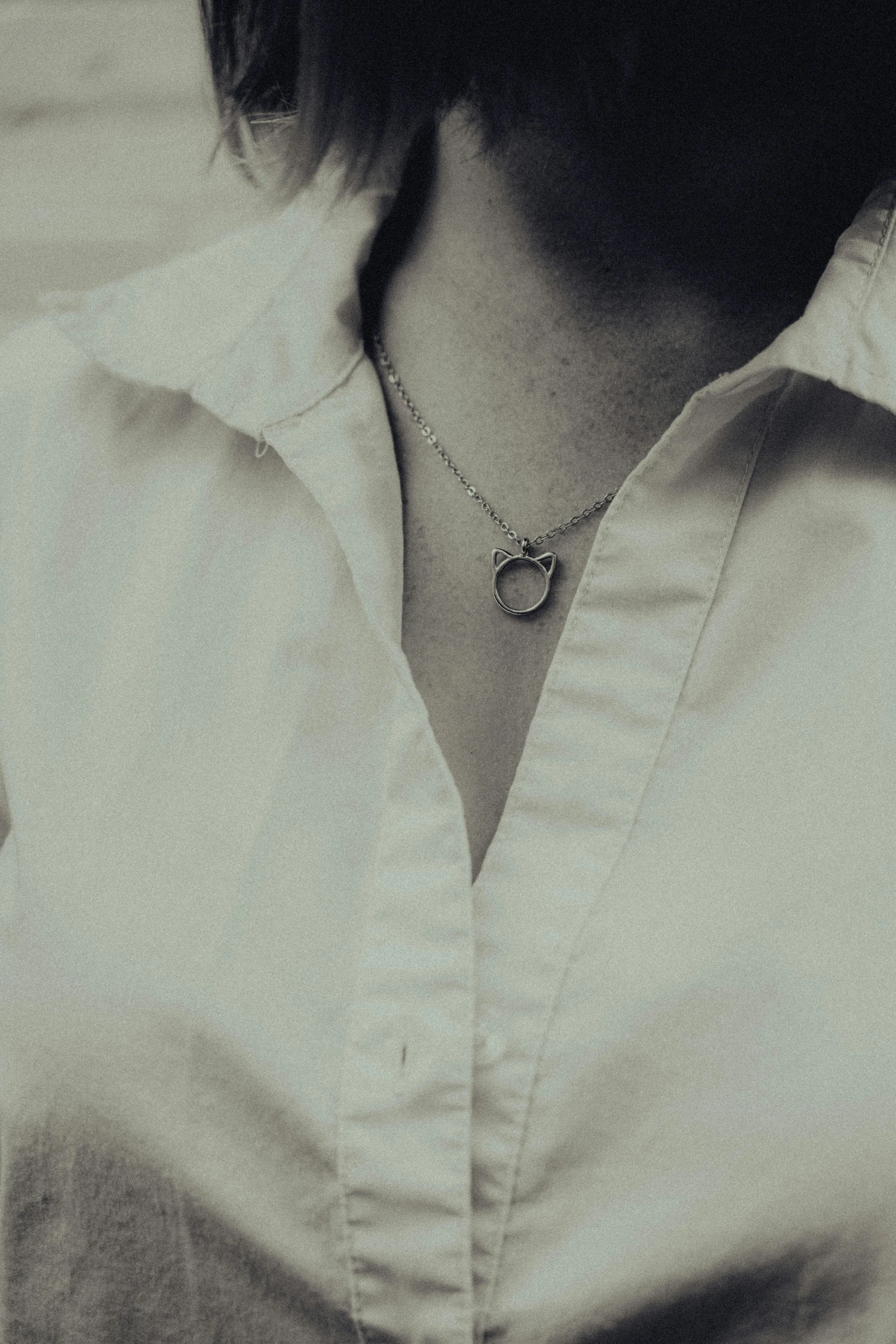 a woman is wearing a white shirt and has a necklace