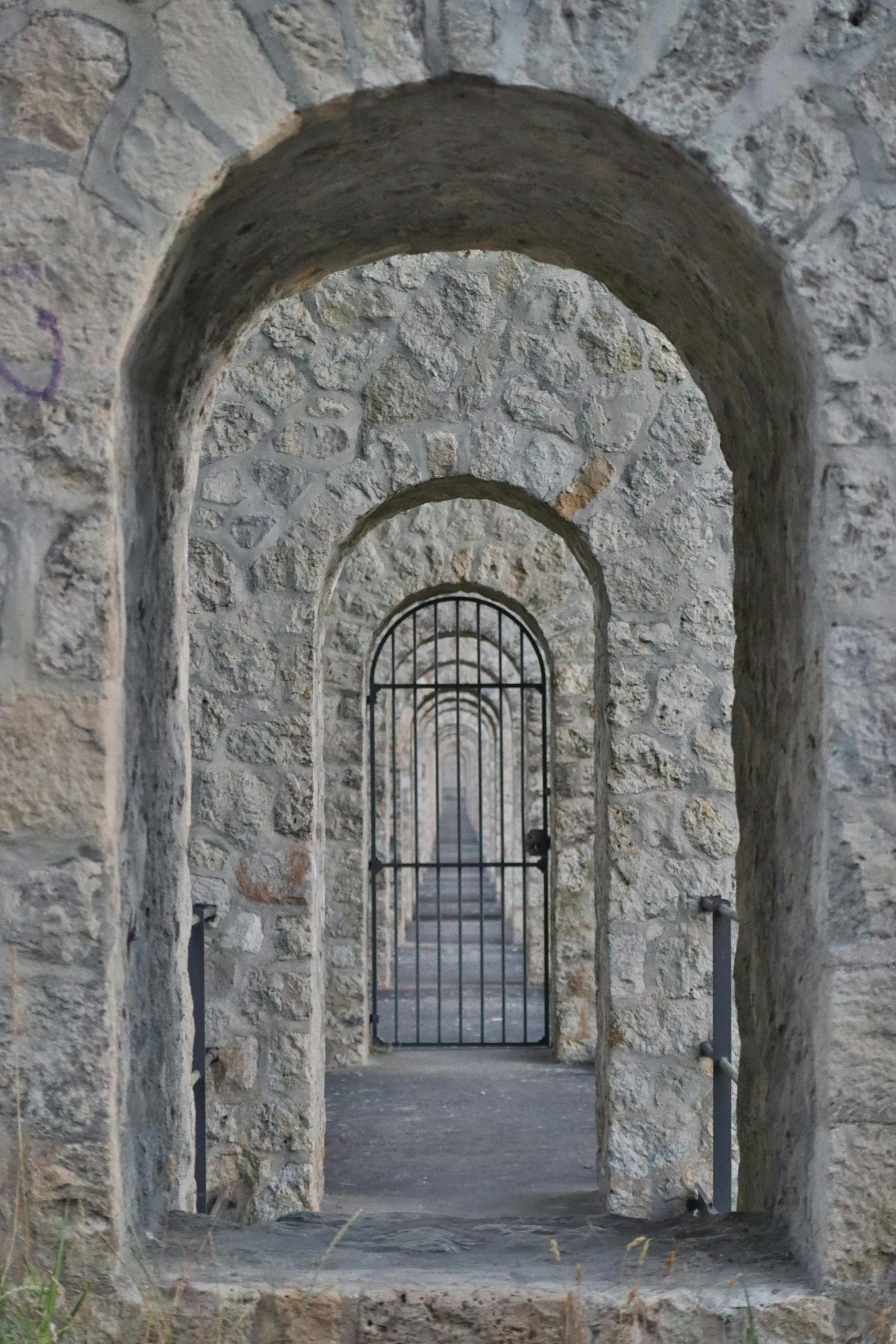 a narrow stone pathway leads to a barred entrance in an old castle