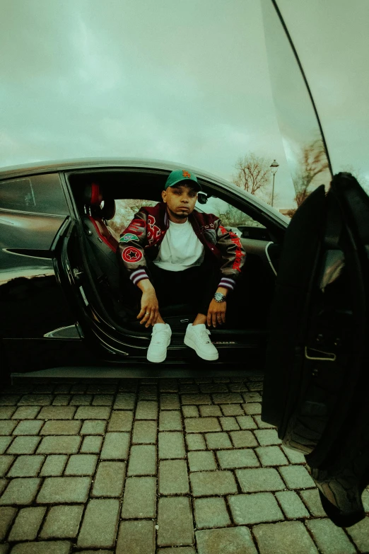 the man sits in his car near a black vehicle