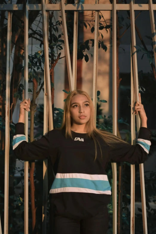 a beautiful woman in a black shirt holding on to an iron gate