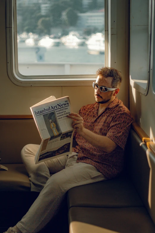 the man is reading the paper on the train