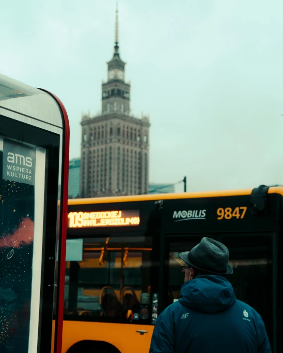 a man standing on the curb next to a yellow bus