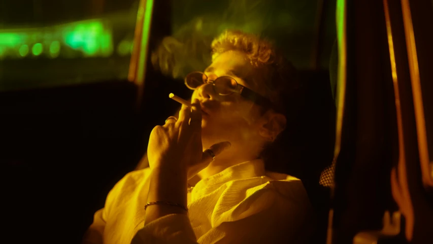 a man sitting down smoking soing next to his face