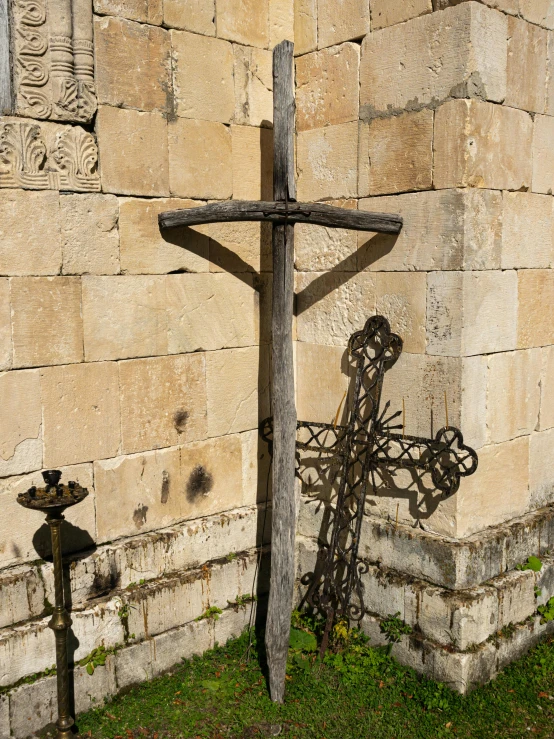 a cross sitting next to a cement wall