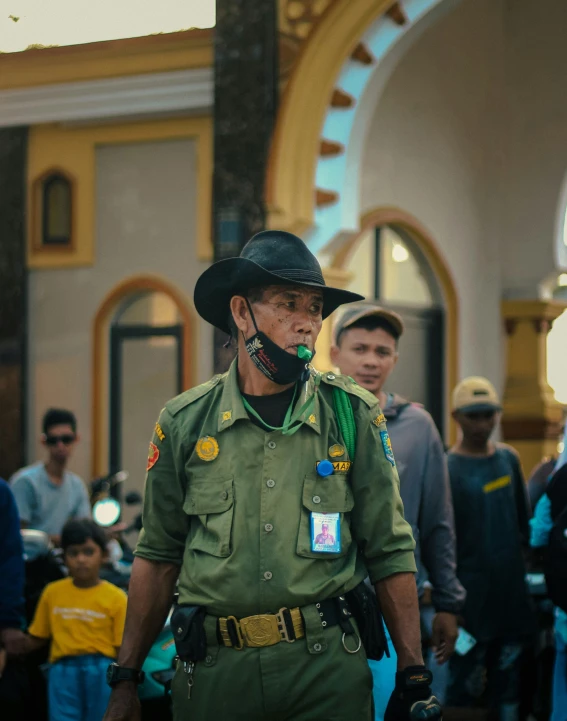 a cop in uniform standing with other people in the background