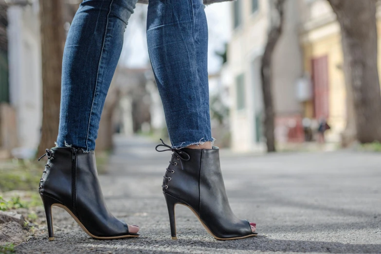 a person wearing black high heel shoes standing on a street