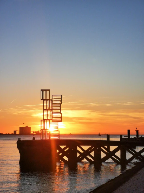 the sun sets over a pier with a water way