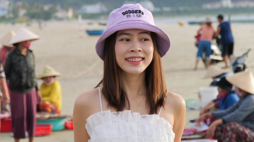 a woman wearing a hat standing in front of a beach