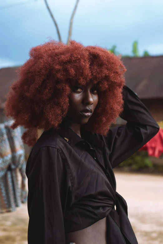 a woman with big red afro is standing outside