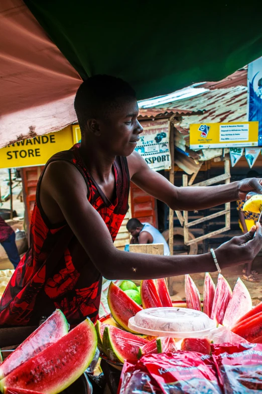 a woman at an outside market  up watermelon