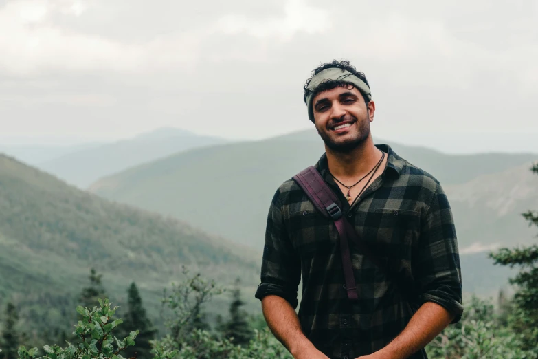 man with camera on shoulder standing at the top of mountain