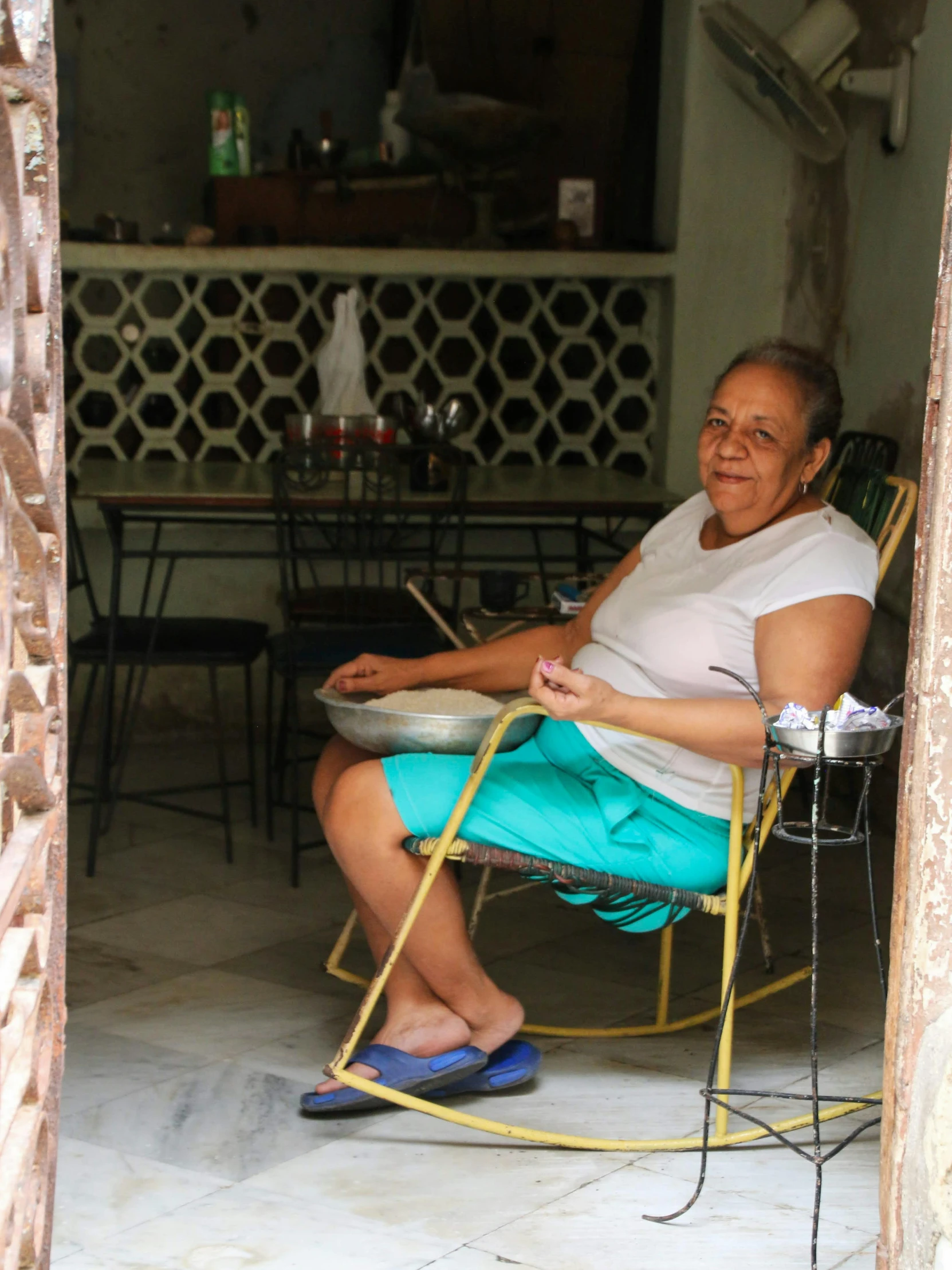 an old lady smiles while sitting in a yellow rocking chair