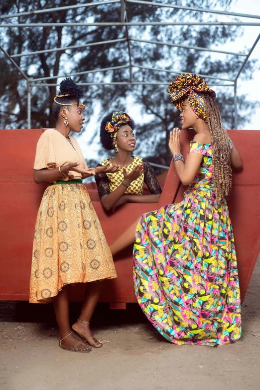 a group of young african women sitting around a red bench