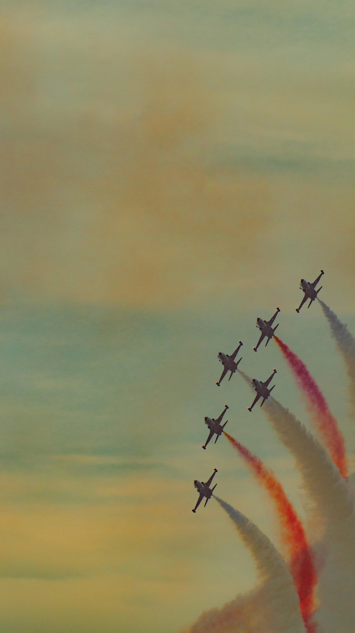 five airplanes fly in formation under a red and blue sky