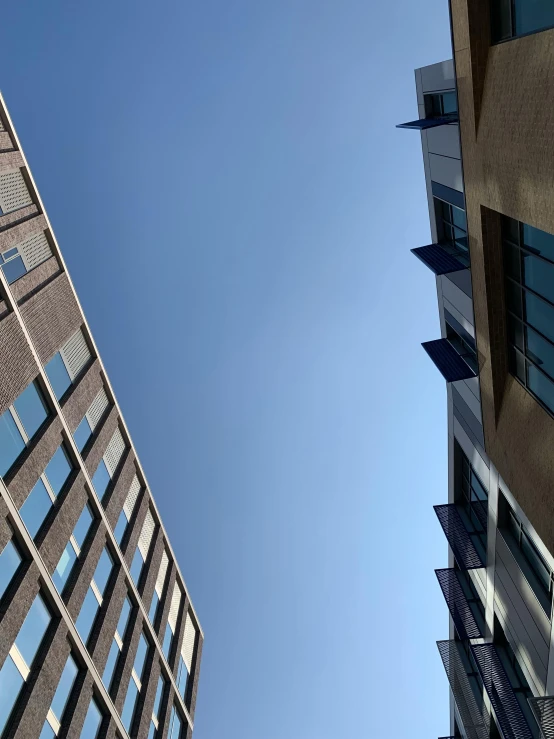 a clear blue sky looking up from the ground at the top of two buildings