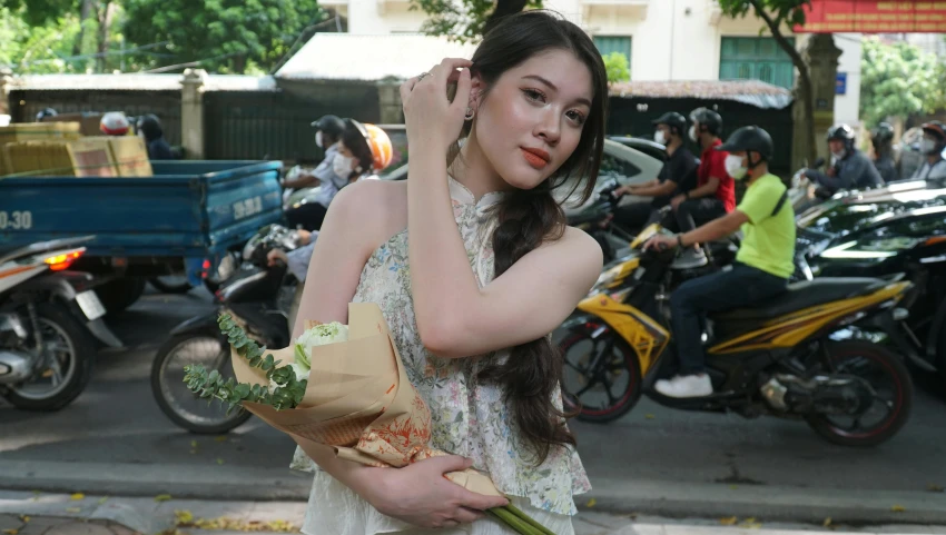 a woman holding flowers on the sidewalk while she walks